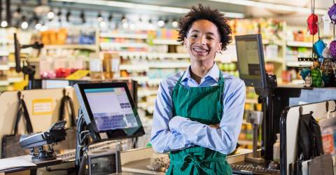 Tiener jongen werkt in supermarkt als kassier