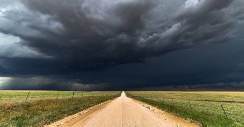 Donker wolken in een weiland boven een weg